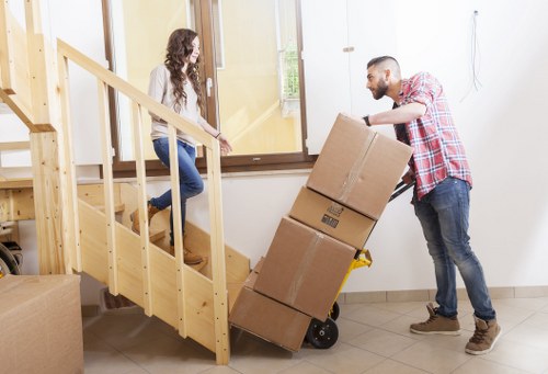 Specialist movers handling a grand piano with protective padding and lifting equipment